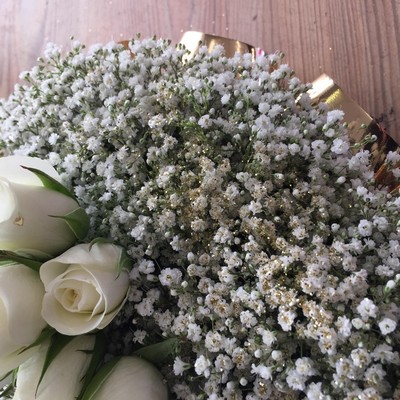 Funeral heart tribute of white gypsophila with gold glitter, gold ribbon edging, and a white rose focal point.