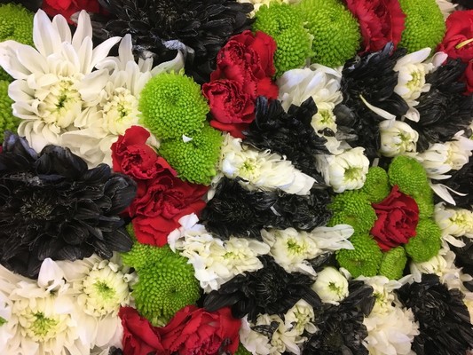 Dart board-shaped funeral tribute made with mixed chrysanthemum and finished with a genuine wired dart board surround, measuring approximately 20 inches.