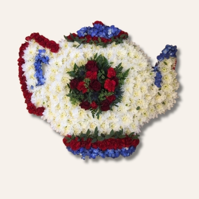 British-themed teapot-shaped funeral tribute made with white chrysanthemum base and red and blue accent flowers, measuring approximately 58cm x 61cm.