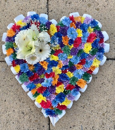 Intricate heart-shaped funeral tribute with sprayed chrysanthemum, white ribbon edge, and white focal flowers.