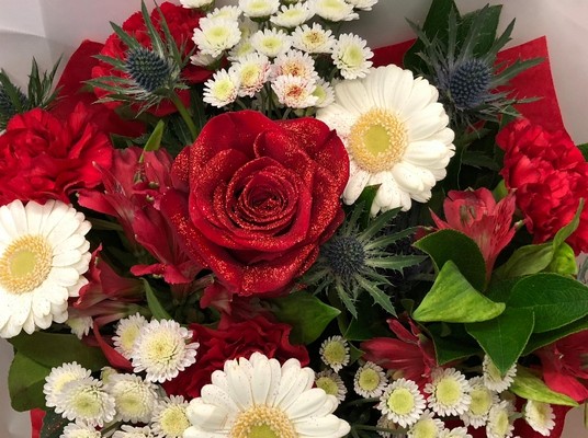 Red, white and blue Christmas bouquet with glittered red roses and mixed seasonal florals, presented in luxury gift wrap.