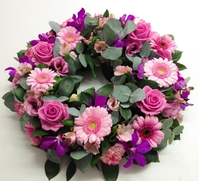 Funeral wreath with mixed pink and cerise florals, accented with eucalyptus and ruscus foliage for a natural, full appearance.
