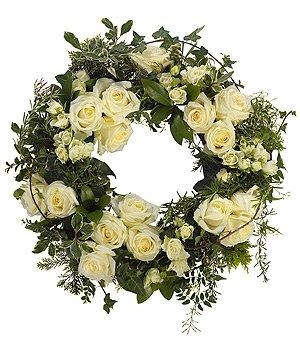 Elegant funeral wreath with luxury white roses and a generous mix of lush foliage.