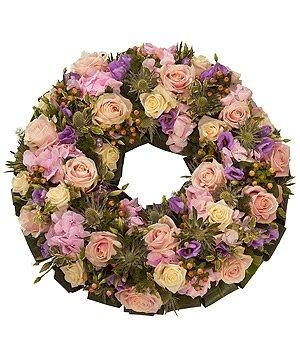 Pastel funeral wreath with mixed luxury seasonal flowers and foliage, symbolising remembrance and grace.