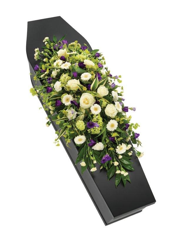  Luxury purple and white casket spray with seasonal florals and lush foliage.