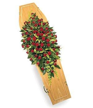 Red rose casket spray with moluccella blooms, green hypericum, and lush green foliage.
