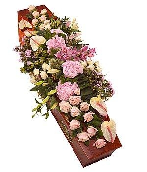 Modern pink casket spray with luxury seasonal flowers and aspidistra leaves.