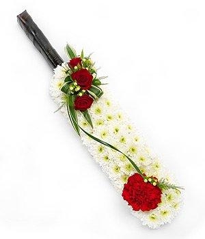 Cricket bat funeral tribute with white chrysanthemums, red roses, and carnations