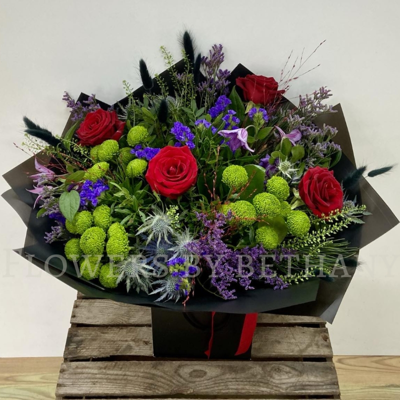 Elena bouquet with red roses, lime green blooms, purple flowers and thistle blue, hand-tied in black wrap.