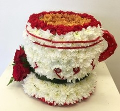 3D tea cup-shaped funeral tribute made with white chrysanthemum, detailed with carnations, roses, foliage, and ribbon, measuring approximately 35cm high by 35cm wide.