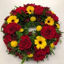 Red and yellow funeral wreath with seasonal flowers and foliage, a fitting tribute for any Manchester United fan.