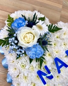 Heart-shaped funeral tribute with laminated wording, white chrysanthemums, delicate ribbon edge, and matching focal. Customisable colour options available.