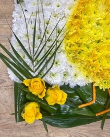 Duck-shaped funeral tribute made with white chrysanthemum, detailed with spray-painted shading and finished with foliage and yellow floral accents on a 2ft x 2ft base.