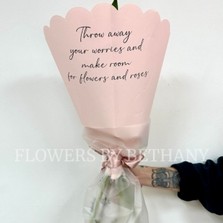 Hand-tied pink bouquet with seasonal florist’s choice florals and greenery, wrapped in scalloped blush pink paper with a satin ribbon.