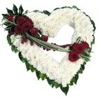 Open heart funeral tribute massed with white chrysanthemums, deep red florals, and flowing mixed foliage.